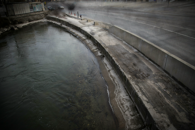 Editorial illustration depicting the somber meeting point of a dark river and a road embankment.