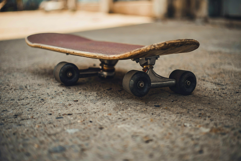A weathered skateboard rests on textured concrete in a softly lit urban setting, symbolizing enduring fitness and dedication.
