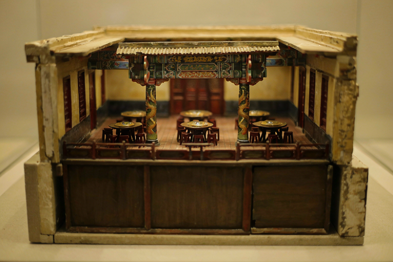 A detailed miniature architectural model of a traditional Chinese restaurant interior, showcasing a canopy supported by columns adorned with dragon and phoenix motifs.