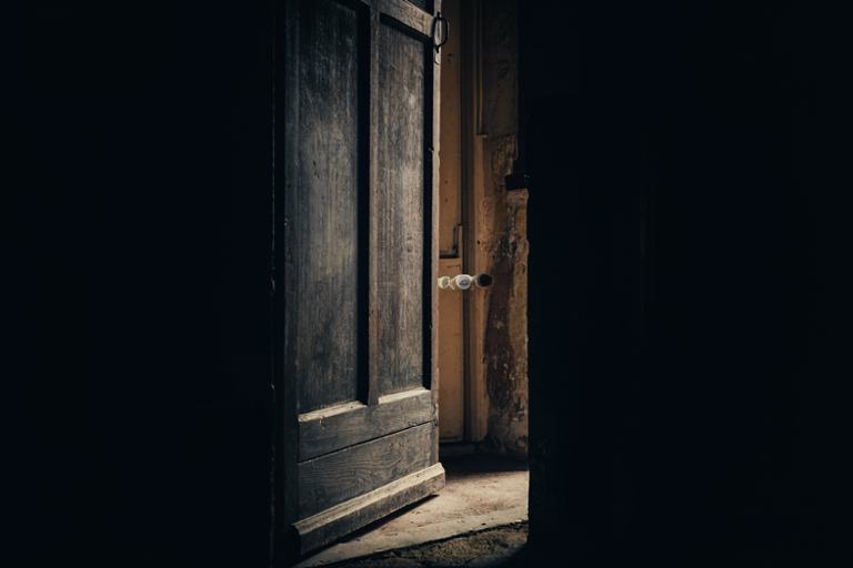 A somber illustration of a heavy, dark wooden door slightly ajar, symbolizing confinement and internal struggle.