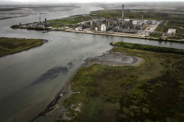 Editorial illustration of an industrial refinery near a polluted river estuary.