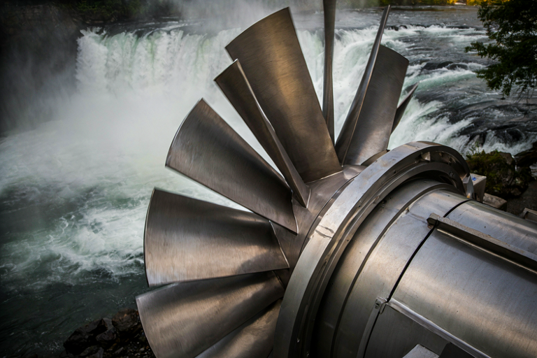 A hydroelectric turbine in a river setting, surrounded by mist and natural landscape.