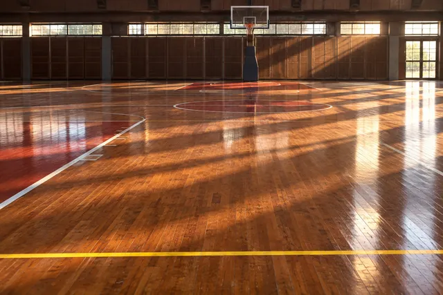 AI illustration based on reference photographs; not an event photograph. An empty, polished wooden basketball court with visible lines and dramatic lighting.