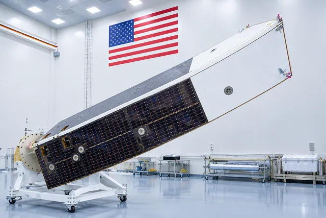 AI illustration based on reference photographs; not an event photograph. Editorial illustration of the NEO Surveyor's sunshade structure with two angled panels and a solar cell array, set in a clean room.