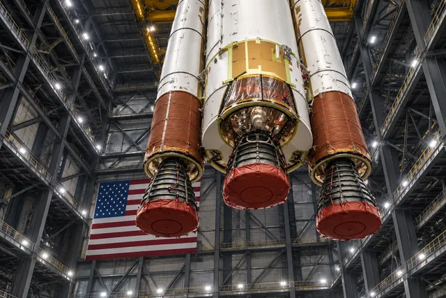 AI illustration based on reference photographs; not an event photograph. An editorial illustration of the SLS core stage integrated with twin solid rocket boosters inside a large industrial assembly building.