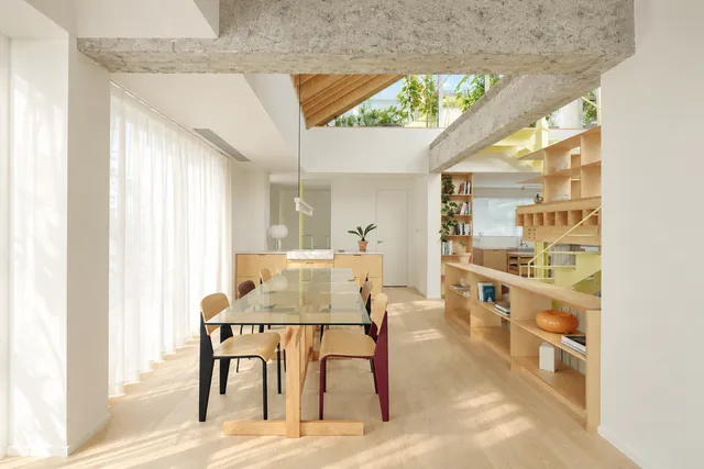 AI illustration based on reference photographs; not an event photograph. Interior view of a modern residence showcasing high ceilings, exposed concrete beams, and a visible staircase leading to an upper level with a kitchen.