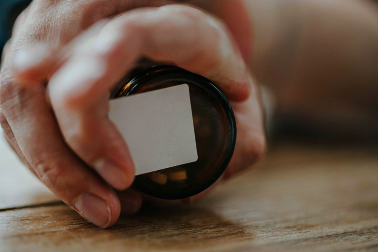 A hand holding a pill bottle in soft light, symbolizing migraine treatment decisions.