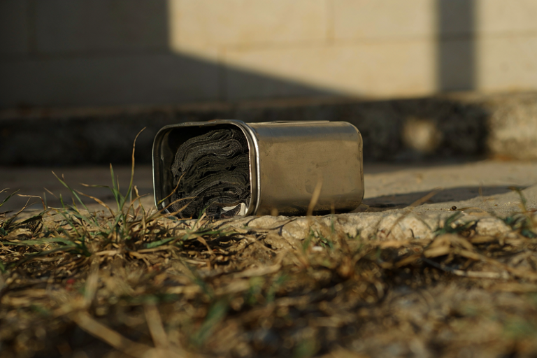 A metal container with wrapped fabric on a grassy surface