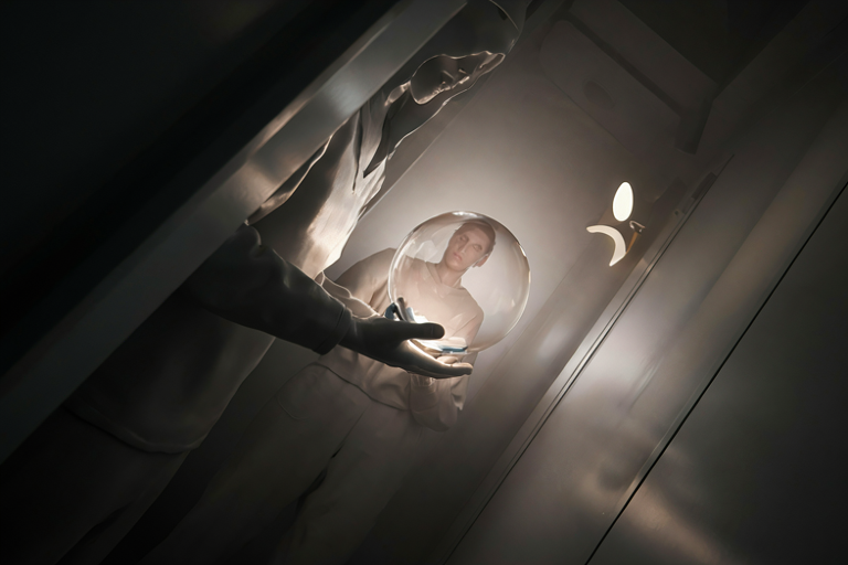 A person holding a glowing orb in a futuristic room with soft lighting and minimalist design.