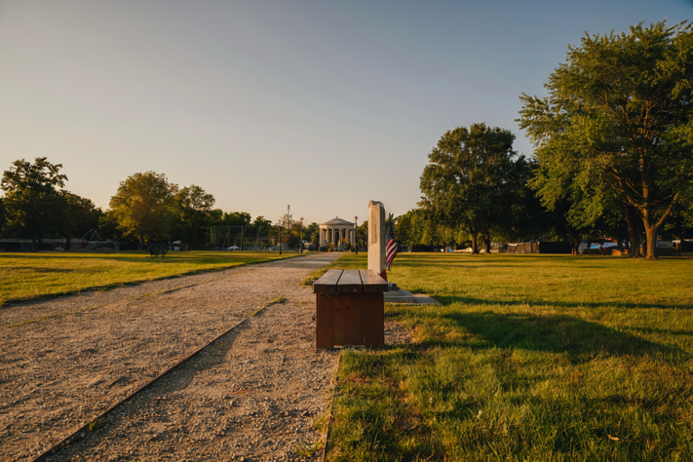 Modernized park bench with distant bandstand and cenotaph