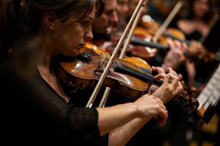 A violinist performing with intense focus, highlighted by dramatic stage lighting.