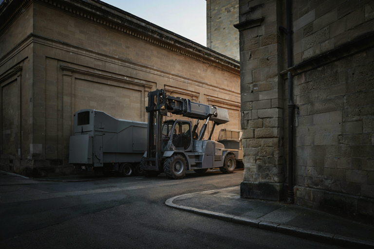 Editorial illustration of heavy machinery near a stone building in the early morning.